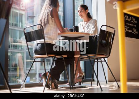 Businesswomen talking at table by window Stock Photo