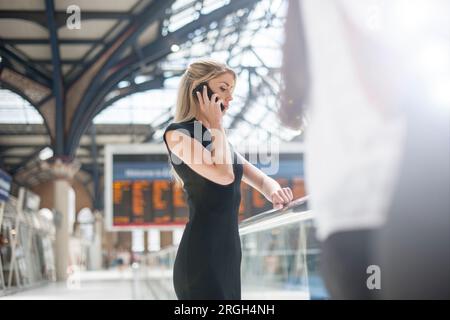 Businesswoman on phone in train station Stock Photo