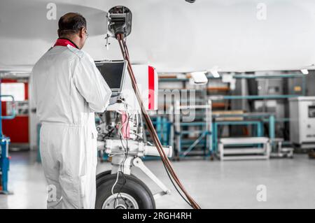 Man using laptop by airplane in hangar Stock Photo
