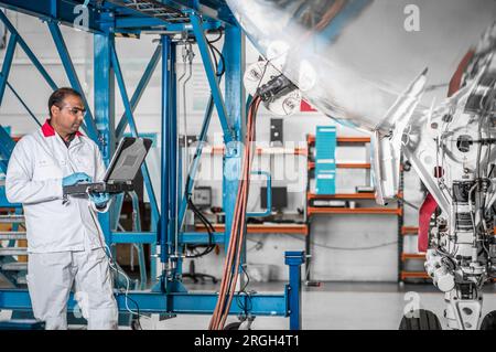 Man using laptop by airplane in hangar Stock Photo