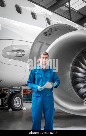 Young man holding digital tablet by airplane engine Stock Photo