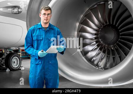 Young man holding digital tablet by airplane engine Stock Photo