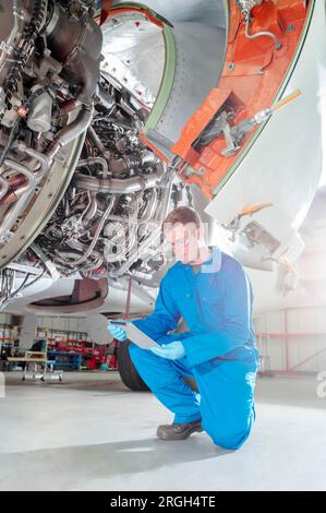 Crouched man using digital table by airplane Stock Photo