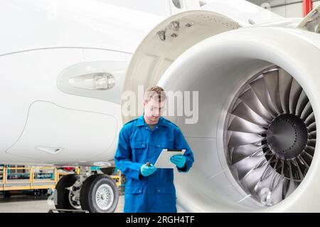 Young man using digital tablet by airplane engine Stock Photo