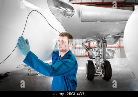 Man working on airplane in hangar Stock Photo