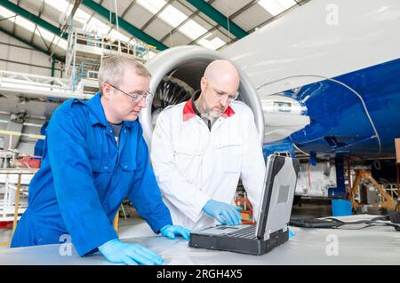 Men using laptop by airplane in hangar Stock Photo