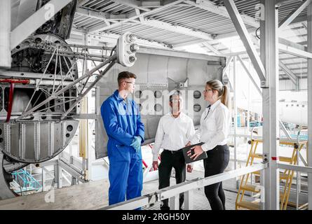 Workers with digital tablet in airplane hangar Stock Photo