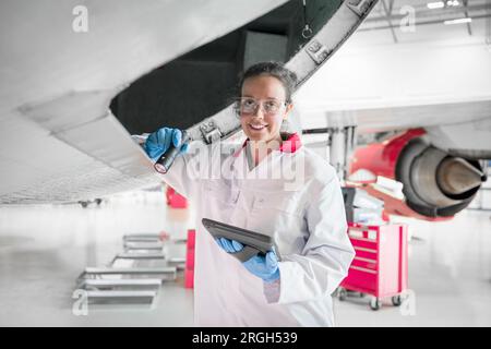 Portrait of young female worker by airplane Stock Photo