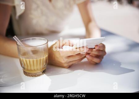 Woman's hands using smart phone by iced coffee Stock Photo