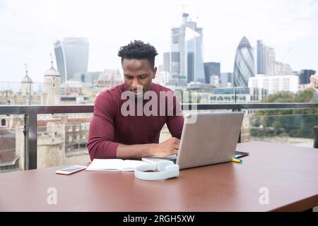 Young man using laptop on balcony Stock Photo