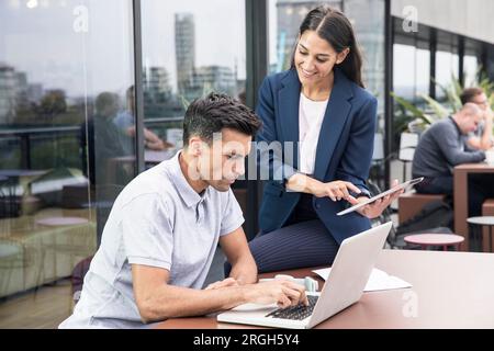 Colleagues using laptop and digital tablet on balcony Stock Photo