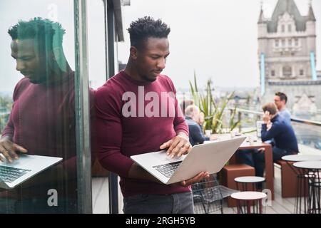 Young man using laptop on balcony Stock Photo