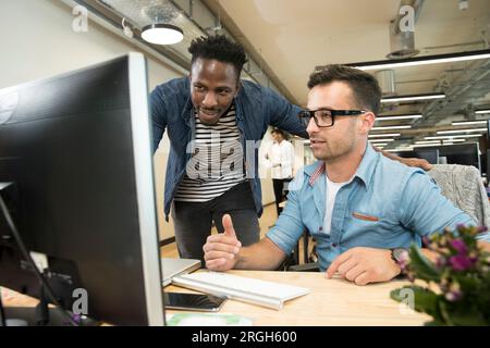 Colleagues using computer Stock Photo