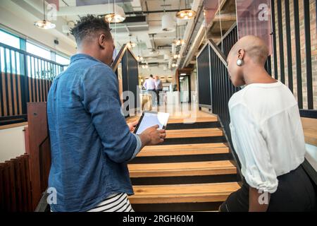 Colleagues using digital tablet on staircase Stock Photo
