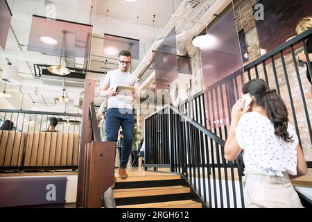 Businesspeople using tablet and smart phone on staircase Stock Photo