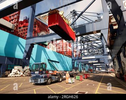 Crane lowering cargo container onto truck at Port of Felixstowe, England Stock Photo