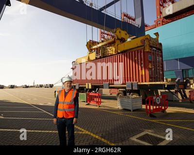 Dock worker by cargo container and truck at Port of Felixstowe, England Stock Photo