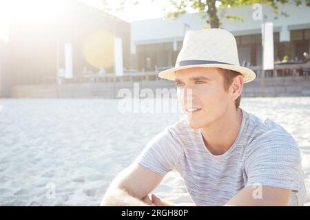 Young man wearing straw trilby hat on beach Stock Photo