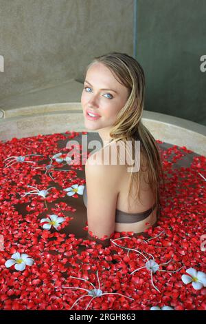 Young woman in bath with flower petals Stock Photo