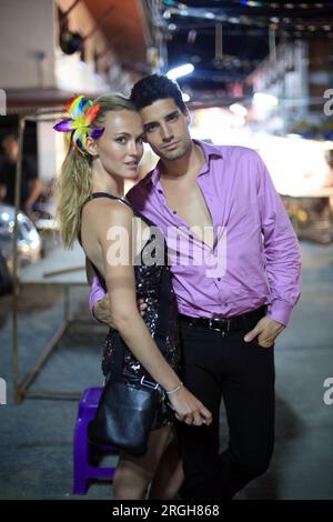 Young couple posing on sidewalk at night Stock Photo