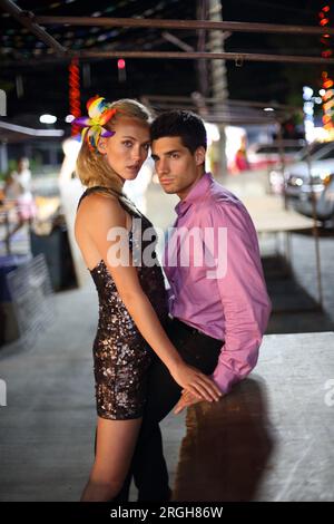Young couple posing on sidewalk at night Stock Photo