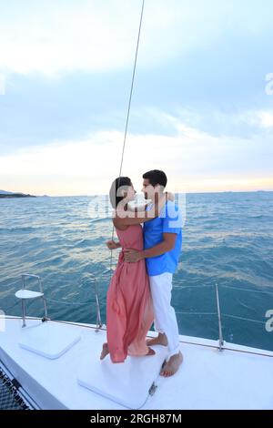 Young couple embracing on yacht at sunset Stock Photo