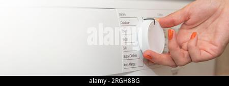 Hands turning on the washing machine close-up. The woman turns on the washing machine and adjusts the duration of the wash. Washing dirty clothes in Stock Photo