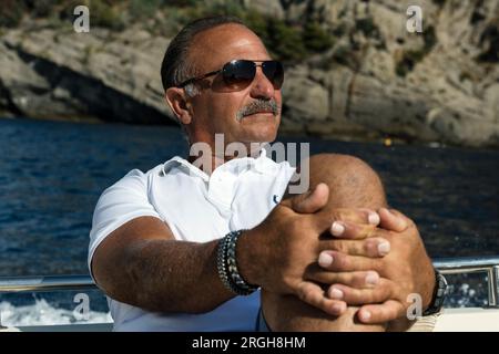 Retired man sightseeing on the coast of Genoa from a boat. Stock Photo