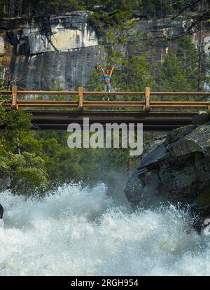 Young woman raising her arms on a bridge Stock Photo