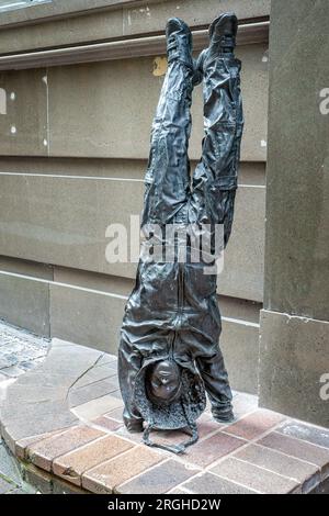 Youngsters - child sized bronze statue of young urchin girl doing a hand stand wearing a hoodie in George Street, Sydney, Australia on 7 January 2023 Stock Photo