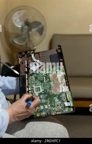computer repairs, old woman in her seventies repairing her laptop, using a screwdriver Stock Photo