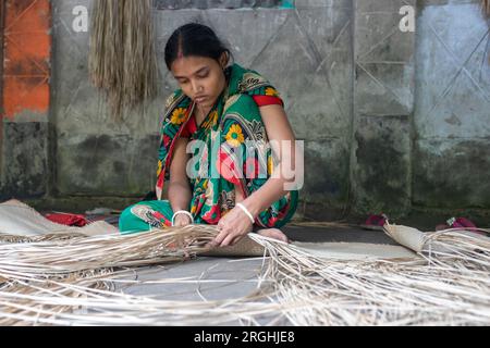 A woman weaves traditional shitol pati (cool mat) at her home in Hailakathi village of Jhalakathi’s Rajapur upazila. Jhalakathi, Bangladesh Stock Photo