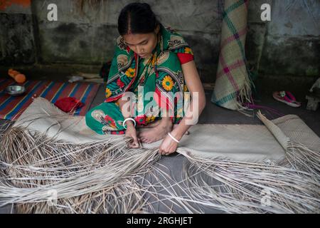 A woman weaves traditional shitol pati (cool mat) at her home in Hailakathi village of Jhalakathi’s Rajapur upazila. Jhalakathi, Bangladesh Stock Photo