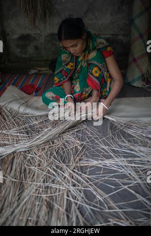 A woman weaves traditional shitol pati (cool mat) at her home in Hailakathi village of Jhalakathi’s Rajapur upazila. Jhalakathi, Bangladesh Stock Photo