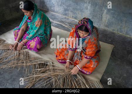 Women weave traditional shitol pati (cool mat) at her home in Hailakathi village of Jhalakathi’s Rajapur upazila. Jhalakathi, Bangladesh Stock Photo