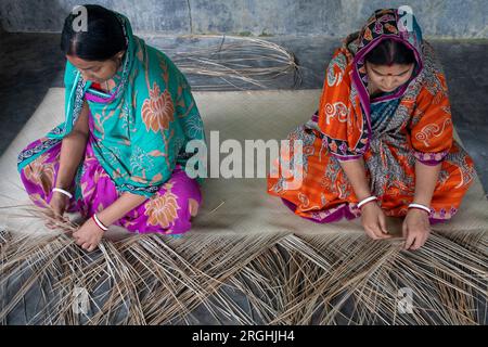 Women weave traditional shitol pati (cool mat) at her home in Hailakathi village of Jhalakathi’s Rajapur upazila. Jhalakathi, Bangladesh Stock Photo