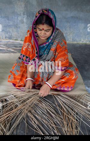 A woman weaves traditional shitol pati (cool mat) at her home in Hailakathi village of Jhalakathi’s Rajapur upazila. Jhalakathi, Bangladesh Stock Photo