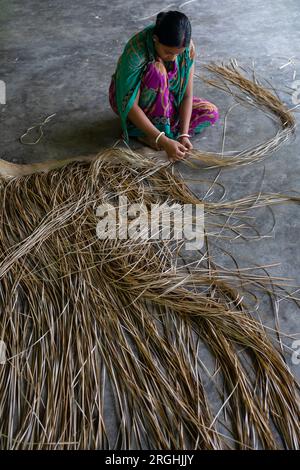 A woman weaves traditional shitol pati (cool mat) at her home in Hailakathi village of Jhalakathi’s Rajapur upazila. Jhalakathi, Bangladesh Stock Photo