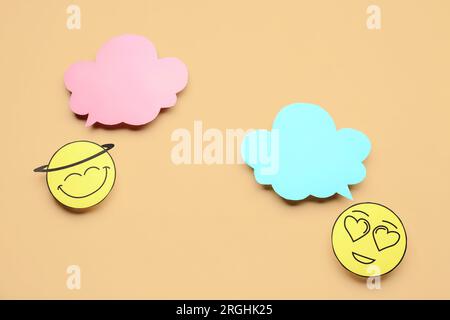 Paper faces with blank speech bubbles on beige background Stock Photo