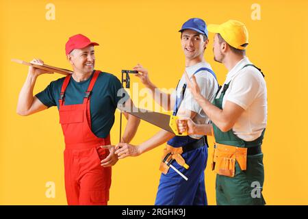 Team of male builders with tools on yellow background Stock Photo