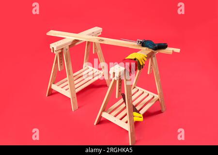 Wooden table with builder's tools on red background Stock Photo