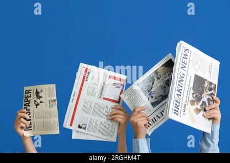 Female hands with different newspapers on blue background Stock Photo