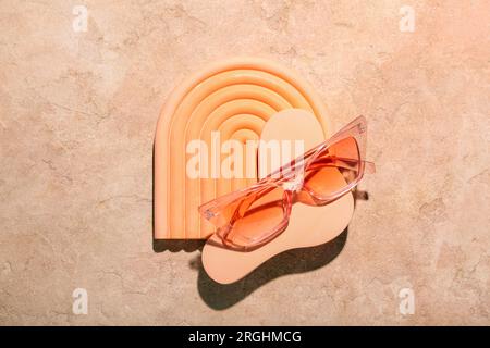 Decorative podiums with stylish sunglasses on orange background Stock Photo