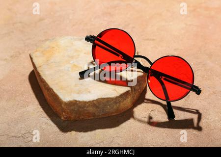 Stone with stylish sunglasses on orange background Stock Photo