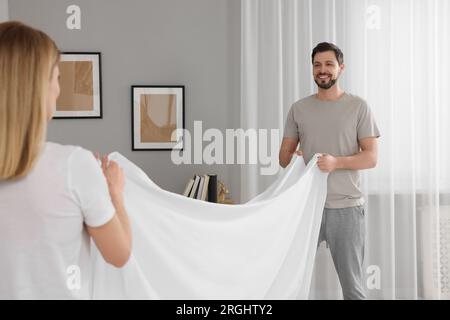 Couple changing bed linens in room. Domestic chores Stock Photo