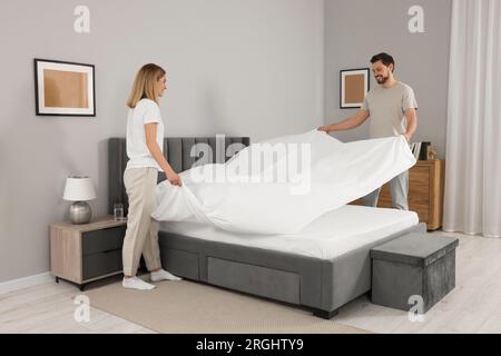 Couple changing bed linens in room. Domestic chores Stock Photo