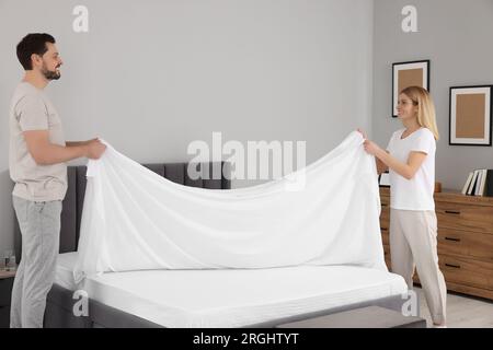 Couple changing bed linens in room. Domestic chores Stock Photo