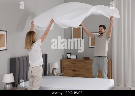 Couple changing bed linens in room. Domestic chores Stock Photo