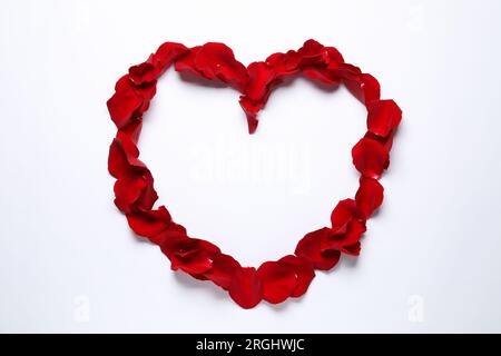 Heart shaped frame of beautiful red rose petals on white background, top view Stock Photo