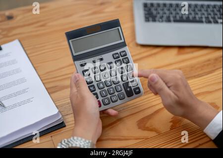 Close-up top view image of a professional businessman using a calculator at his desk. income, budget, financial, tax, sales Stock Photo